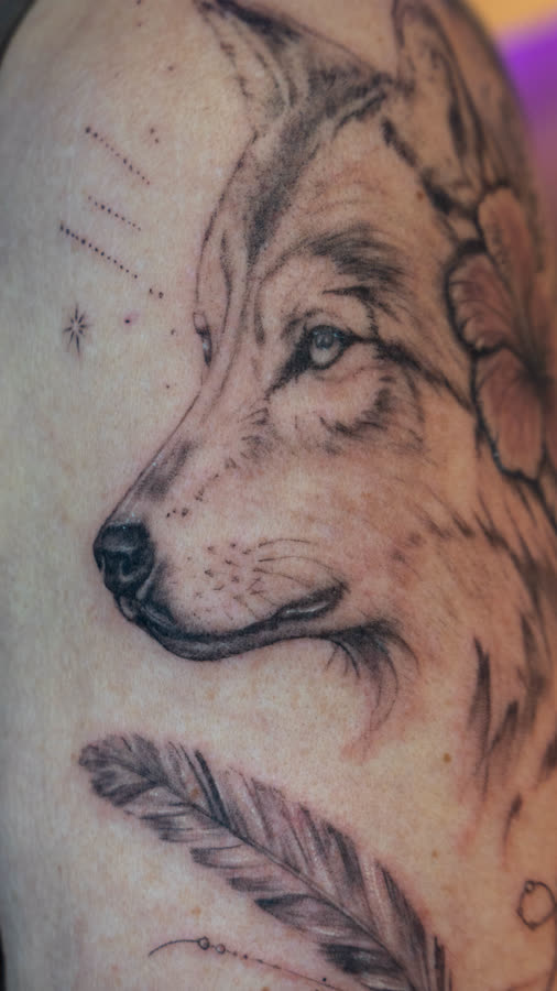 Black & Grey Wolf mit Feder und feinen Punktlinien am Oberarm